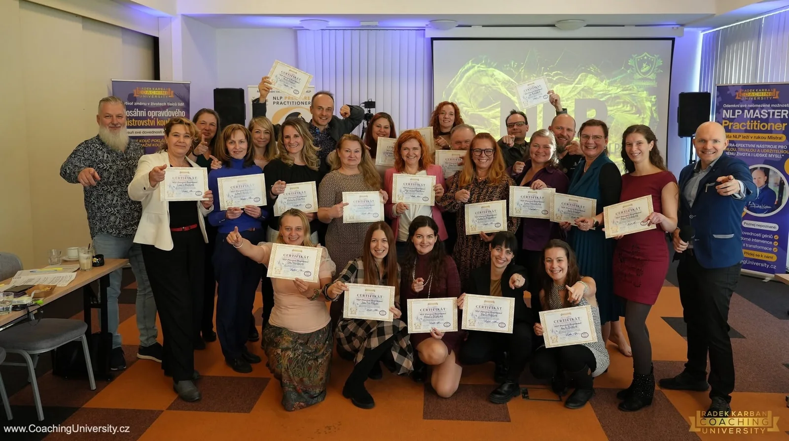 Skupina absolventů výcviku NLP Premiere Practitioner s mezinárodními certifikáty spolu s Radkem Karbanem