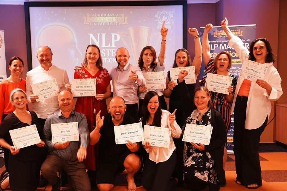 Skupina absolventů drží certifikáty NLP Master, ruce nahoře a smích